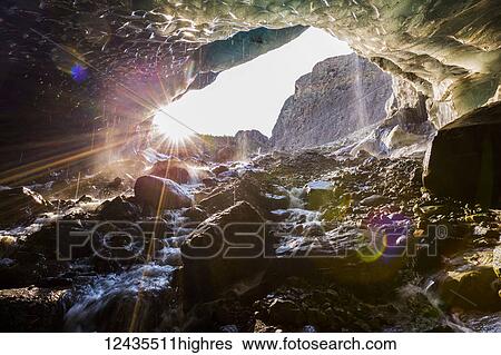 Stock Photograph - The sun shines into a cave beneath the ice of Root Glacier in Wrangell-St. Elias National Park; Alaska, United States of America. Fotosearch