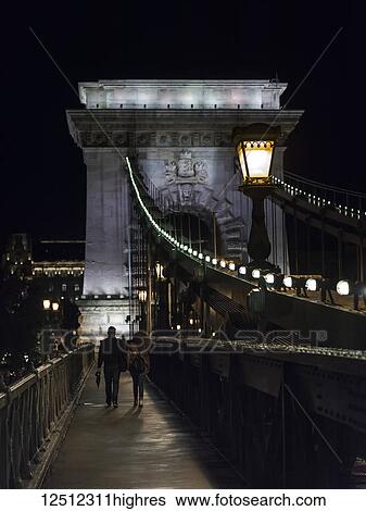 Stock Photograph - The Szechenyi Chain Bridge at nighttime, a suspension bridge over the Danube river; Budapest, Budapest, Hungary. Fotosearch