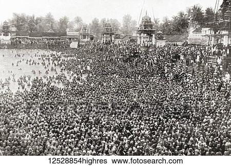 Stock Photograph - Thousands of Hindus bathing in the sacred River Ganges, India. They are celebrating the avatarana or descent of the Ganges from heaven to earth, bathing in the Ganges on this day is said to rid the bather of ten sins. From The Wonders of the World,.... Fotosearch