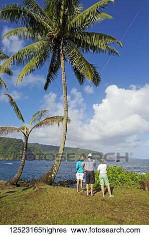 Stock Photograph - Three tourists looking at the North coast of Maui as viewed from Keanae, on the way to Hana; Maui, Hawaii, United States of America. Fotosearch