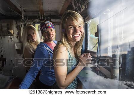 Stock Photograph - Three young women hanging out in an abandoned vintage ship along coastal Homer, South-central Alaska; Homer, Alaska, United States of America. Fotosearch