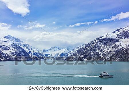 Stock Photograph - Tour boat cruises past Johns Hopkins Glacier in Glacier Bay National Park and Preserve; Alaska, United States of America. Fotosearch
