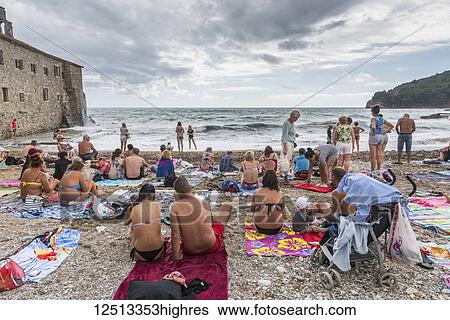 Stock Photograph - Tourists in bathing suits on the beach on the Bay of Kotor; Budva, Budva Municipality, Monte. Fotosearch