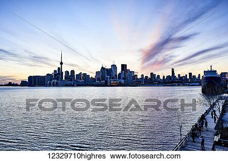Tourists On A Boardwalk With A View Of The Downtown City Skyline At Dusk; Toronto, Ontario, Canada View Large Photo Image Stock Photograph - Tourists On A Boardwalk With A View Of The Downtown City Skyline At Dusk; Toronto, Ontario, Canada. Fotosearch