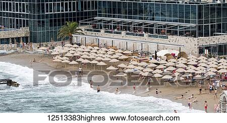Stock Photograph - Tourists on the beach outside a hotel in Budva on the coast of Monte; Budva, Opstina Budva, Monte. Fotosearch