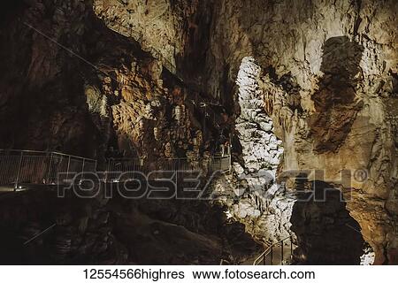 Stock Photograph - Tourists views stalagmites in an underground cave; Italy. Fotosearch