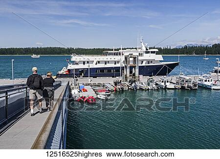 Stock Photograph - Tourists walk down a ramp towards the Safari Explorer sightseeing boat, Bartlett Cove, Glacier Bay National Park, Southeast Alaska; Alaska, United States of America. Fotosearch