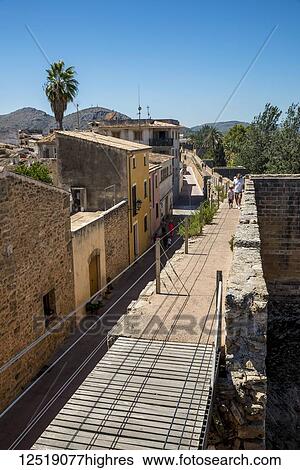Stock Photograph - Tourists walking over the city wall; Alcudia, Mallorca, Balearic Islands, Spain. Fotosearch