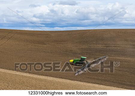 Stock Photograph - Track Tractor Configured With Spraying Booms Spraying Fertilizer On A Garbonzo Bean Seedbed In The Palouse Region Of Eastern Washington; Washington, United States Of America. Fotosearch