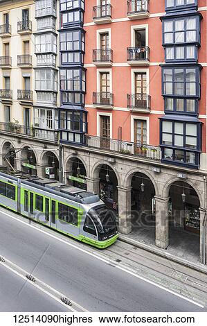 Stock Photograph - Tranvia, at a stop in front of a building opposite the Ribera Municipal Market; Bilbao, Vizcaya, Pais Vasco, Spain. Fotosearch