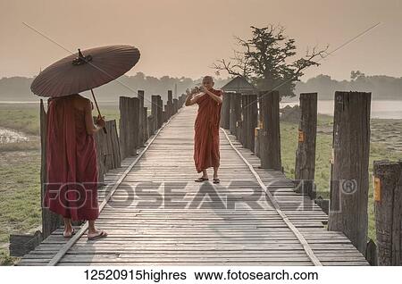 Two Buddhist monks on a boardwalk, one talking a picture with a camera of another holding an umbrella; Mandalay, Myanmar View Large Photo Image Stock Photograph - Two Buddhist monks on a boardwalk, one talking a picture with a camera of another holding an umbrella; Mandalay, Myanmar. Fotosearch