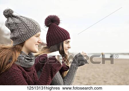 Two friends at the beach wearing knit hats and scarves, sitting and having coffee together, Woodbine Beach; Toronto, Ontario, Canada View Large Photo Image Stock Photograph - Two friends at the beach wearing knit hats and scarves, sitting and having coffee together, Woodbine Beach; Toronto, Ontario, Canada. Fotosearch