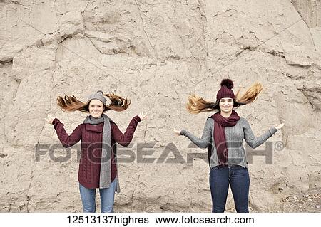 Stock Photograph - Two friends standing in front of the Scarborough Bluffs and flipping hair up; Scarborough, Ontario, Canada. Fotosearch