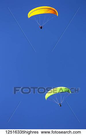 Stock Photograph - Two paragliders flying with a blue sky background; Grainau, Bavaria, Germany. Fotosearch
