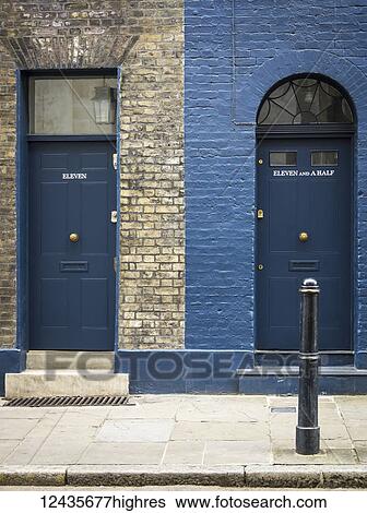 Stock Photograph - Two residential doorways side by side, one numbered eleven and the other eleven and a half, with differing facade and windows for each; London, England. Fotosearch