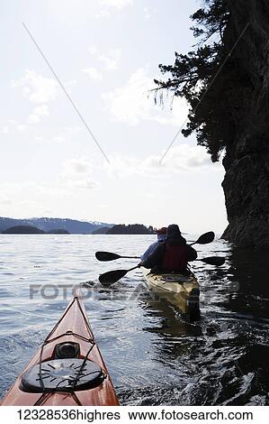Stock Photograph - Two sea kayakers in a double sea kayak, Kachemak Bay, Southcentral Alaska; Alaska, United States of America. Fotosearch