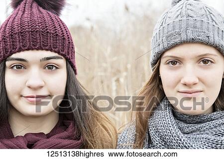 Stock Photograph - Two teenage girls wearing knit hats and scarves and looking at the camera; Scarborough, Ontario, Canada. Fotosearch
