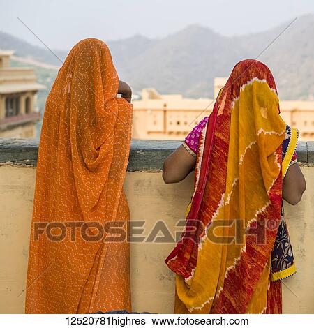 Two women in colourful traditional Indian clothing stand talking and looking out in Amer Fort; Jaipur, Rajasthan, India View Large Photo Image Stock Photograph - Two women in colourful traditional Indian clothing stand talking and looking out in Amer Fort; Jaipur, Rajasthan, India. Fotosearch