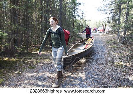 Stock Photograph - Two women portaging a canoe in the Swanson Lake are, Kenai Peninsula, South-central Alaska; Alaska, United States of America. Fotosearch