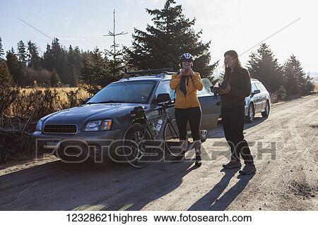 Stock Photograph - Two women preparing for a bike ride near Homer, Kenai Peninsula, South-central Alaska; Alaska, United States of America. Fotosearch