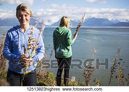 Stock Photograph - Two women sit on bluff overlooking Kachemak Bay on an autumn day, South-central Alaska; Homer, Alaska, United States of America. Fotosearch