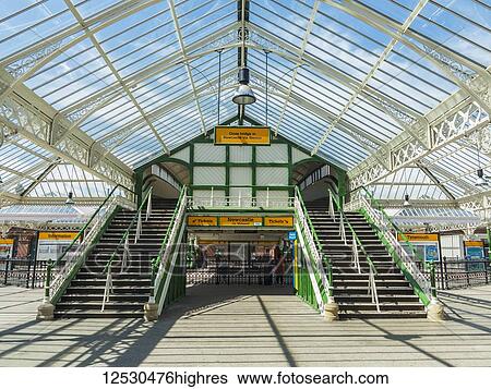 Stock Photograph - Tynemouth station, with a bright blue sky throwing shadows on the ground through a glass roof; Tynemouth, England. Fotosearch