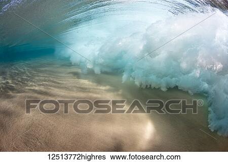 Stock Photograph - Underwater view of a breaking wave as the surf crashes over a sandy bottom off the island of Maui; Maui, Hawaii, United States of America. Fotosearch