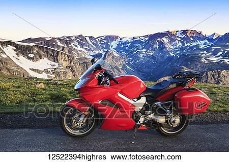 Stock Photograph - View from the Beartooth Highway of the Beartooth Mountains and a motorcycle parked on the roadside; Cody, Wyoming, United States of America. Fotosearch