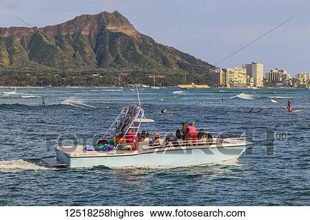 Stock Photograph - View of Diamond Head, Waikiki, a Hawaiian Parasail boat and surfing from Magic Island, Ala Moana Beach Park; Honolulu, Oahu, Hawaii, United States of America. Fotosearch