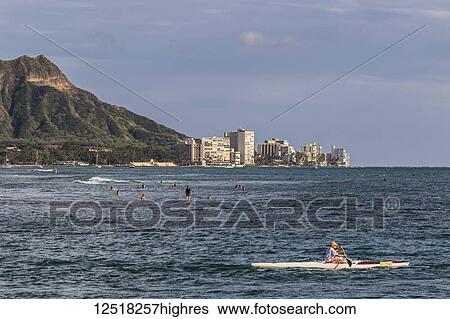 Stock Photograph - View of Diamond Head, Waikiki, and the two major Hawaiian watersports outrigger canoeing and surfing, from Magic Island, Ala Moana Beach Park; Honolulu, Hawaii, United States of America. Fotosearch