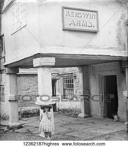 Stock Photograph - Vintage picture in black and white of a young girl standing in front of Keigwin Arms Hotel; Mousehole, Cornwall, England. Fotosearch