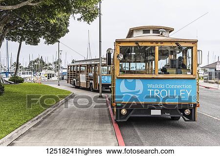 Stock Photograph - Waikiki trolleys waiting for passengers on Holomoana Street near the Ala Wai boat harbor (in background) in Waikiki; Honolulu, Oahu, Hawaii, United States of America. Fotosearch