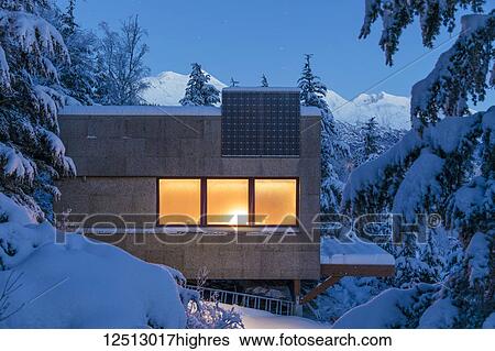 Warm light emanates from a cabin in a snow-covered landscape, solar panels on the roof of the cabin, cool light at dusk casts soft light on distant snow-covered Kenai Mountains, South-central Alaska in winter; Moose Pass, Alaska, United States of America View Large Photo Image Stock Photograph - Warm light emanates from a cabin in a snow-covered landscape, solar panels on the roof of the cabin, cool light at dusk casts soft light on distant snow-covered Kenai Mountains, South-central Alaska in winter; Moose Pass, Alaska, United States of America. Fotosearch