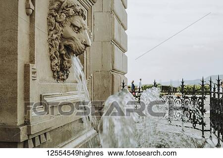 Stock Photograph - Water fountain out of lion's mouth on the facade of a historic building; Italy. Fotosearch