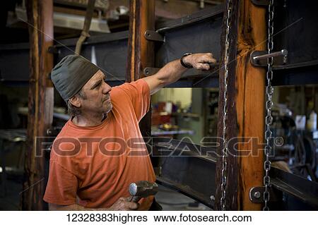 Welder And Metal Work Artist Doug Schwiesow Working On A Custom Sign Designed With A Local Artist For The Kenai Peninsula College Kachemak Bay Campus. View Large Photo Image Stock Photograph - Welder And Metal Work Artist Doug Schwiesow Working On A Custom Sign Designed With A Local Artist For The Kenai Peninsula College Kachemak Bay Campus.. Fotosearch