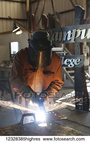Stock Photograph - Welder And Metal Work Artist Doug Schwiesow Working On A Custom Sign Designed With A Local Artist For The Kenai Peninsula College Kachemak Bay Campus.. Fotosearch