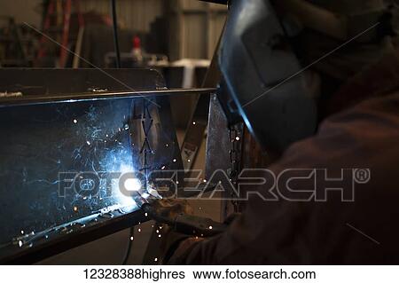 Stock Photograph - Welder And Metal Work Artist Doug Schwiesow Working On A Custom Sign Designed With A Local Artist For The Kenai Peninsula College Kachemak Bay Campus.. Fotosearch