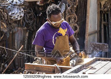 Stock Photograph - Welder at the Medeber Market, where artisans recycle old tyres and tins to make new artifacts; Asmara, Central Region, Eritrea. Fotosearch