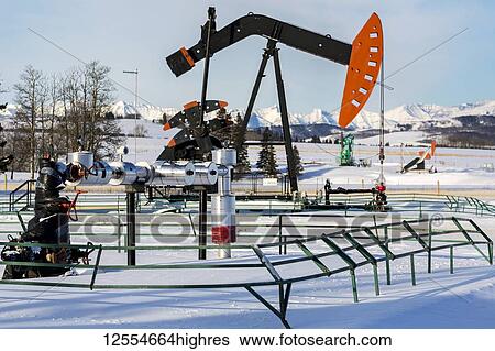 Well head with pipeline and pumpjack in a snow-covered field with snow-covered mountains and blue sky in the background, North of Longview; Alberta, Canada View Large Photo Image Stock Photograph - Well head with pipeline and pumpjack in a snow-covered field with snow-covered mountains and blue sky in the background, North of Longview; Alberta, Canada. Fotosearch
