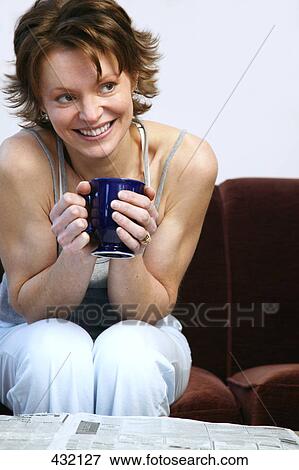 Stock Photo - Woman drinking coffee in front of newspaper. Fotosearch