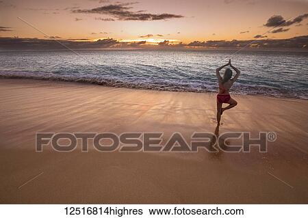 Woman in a yoga pose on the beach at sunset; Molokai, Oahu, Hawaii, United States of America View Large Photo Image Stock Photograph - Woman in a yoga pose on the beach at sunset; Molokai, Oahu, Hawaii, United States of America. Fotosearch