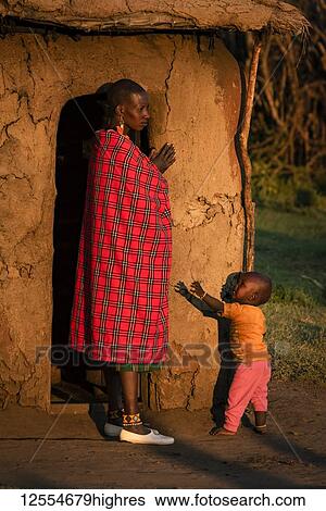 Stock Photograph - Woman in shuka with child outside hut; Tanzania. Fotosearch