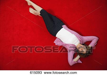 Stock Image - Woman relaxes by laying on floor. Fotosearch