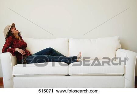 Stock Image - Woman relaxes on sofa. Fotosearch