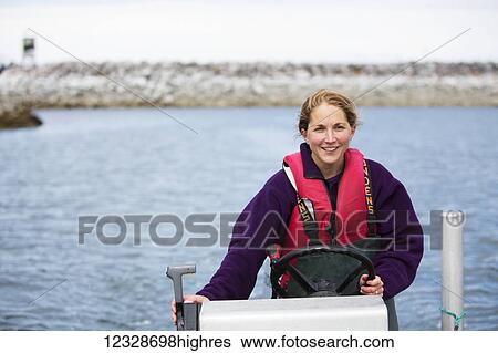 Stock Photograph - Woman set-netter drives a set-net skiff in Seldovia Bay, South-central Alaska; Alaska, United States of America. Fotosearch