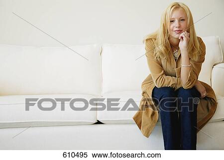 Stock Photography - Woman sits on sofa. Fotosearch
