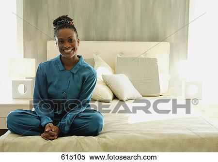 Woman sits on the edge of a bed View Large Photo Image Stock Photography - Woman sits on the edge of a bed. Fotosearch