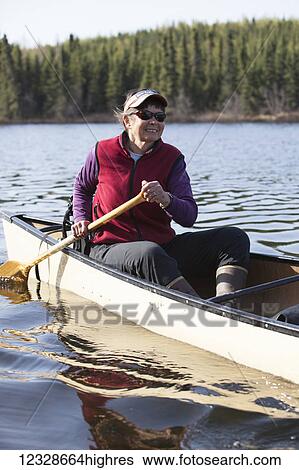 Stock Photograph - Woman steering a canoe in the Swanson Lake area, Kenai Peninsula, South-central Alaska; Alaska, United States of America. Fotosearch