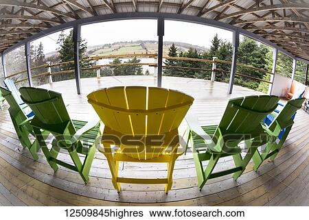 Stock Photograph - Yellow and green adirondack chairs on a wooden covered deck with a view, Gardens of Hope respite cabin; New Glasgow, Prince Edward Island, Canada. Fotosearch