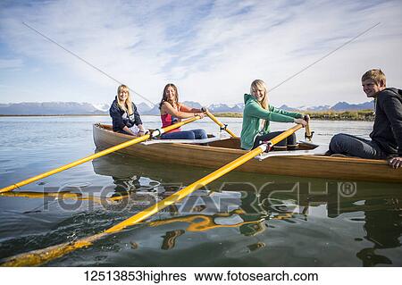Stock Photograph - Young adults rowing in a canoe, South-central Alaska; Homer, Alaska, United States of America. Fotosearch
